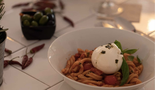 Pasta with burrata on a table with olives on the side